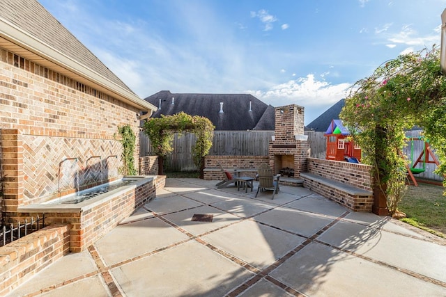 view of patio / terrace with a playground and an outdoor brick fireplace