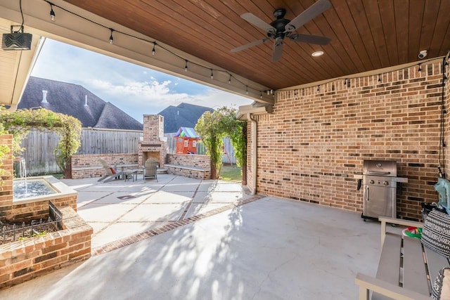 view of patio featuring an outdoor brick fireplace, a grill, a mountain view, and ceiling fan