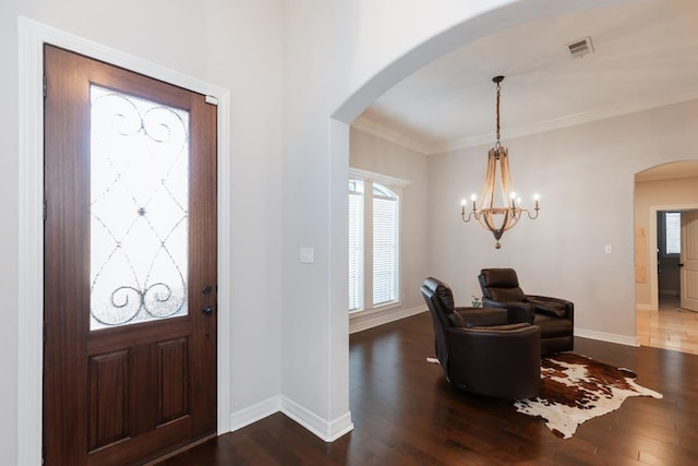 entrance foyer with dark wood-type flooring, a chandelier, and ornamental molding