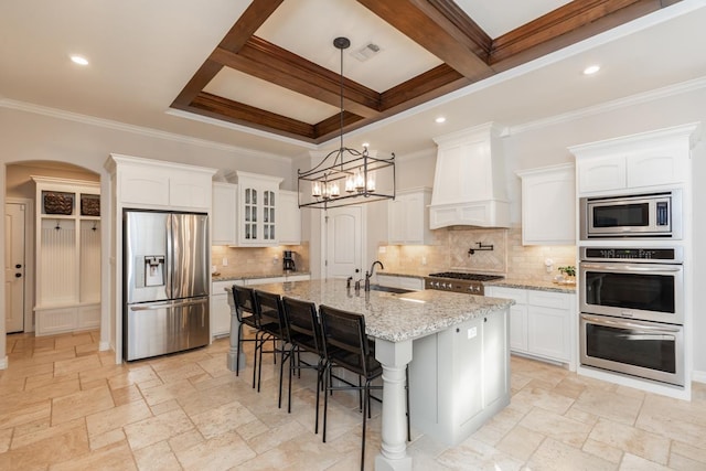 kitchen featuring premium range hood, a center island with sink, sink, beamed ceiling, and stainless steel appliances