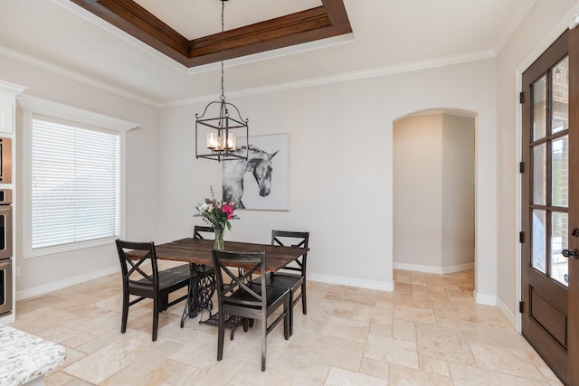 dining space with a tray ceiling, crown molding, and a chandelier