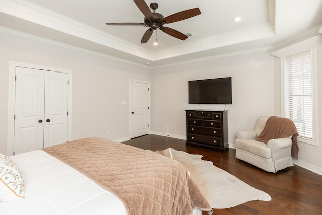 bedroom with ceiling fan, multiple windows, dark hardwood / wood-style flooring, and a raised ceiling