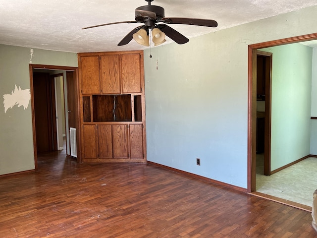 unfurnished room featuring ceiling fan, dark hardwood / wood-style flooring, and a textured ceiling