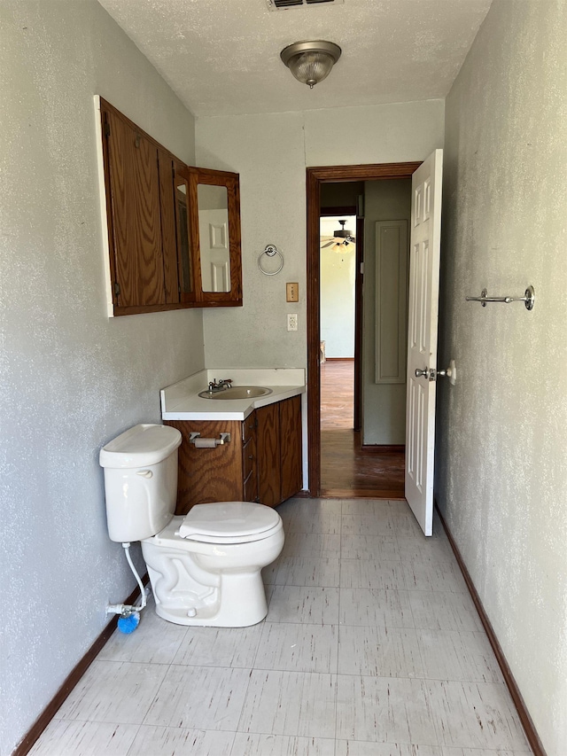 bathroom featuring vanity, ceiling fan, toilet, and a textured ceiling