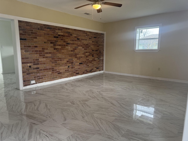 spare room with ceiling fan and brick wall