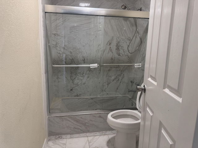 bathroom featuring toilet and shower / bath combination with glass door