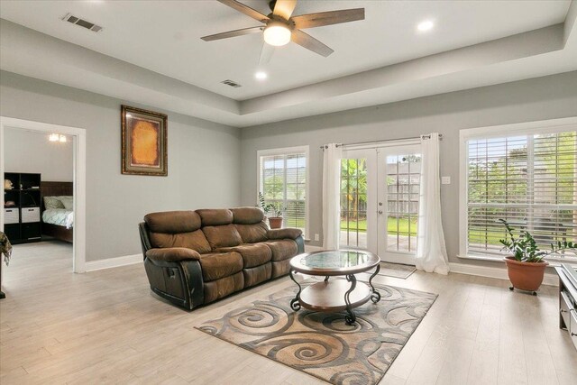 living room featuring a wealth of natural light, french doors, ceiling fan, and light hardwood / wood-style floors