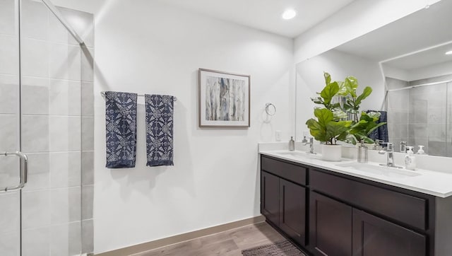 full bathroom featuring double vanity, a sink, a stall shower, and wood finished floors