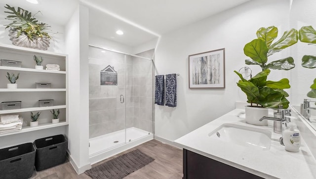 full bathroom featuring a sink, double vanity, wood finished floors, and a shower stall