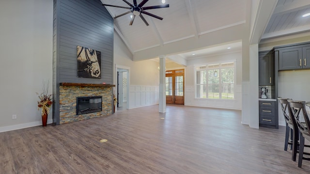 living room featuring beam ceiling, a fireplace, high vaulted ceiling, and wood-type flooring