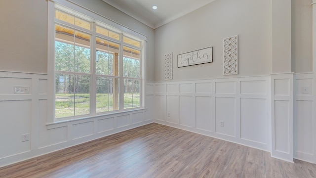 empty room featuring ornamental molding, a healthy amount of sunlight, and light hardwood / wood-style floors