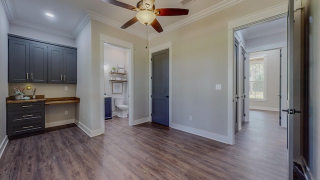 interior space featuring crown molding, ensuite bath, ceiling fan, built in desk, and dark hardwood / wood-style flooring