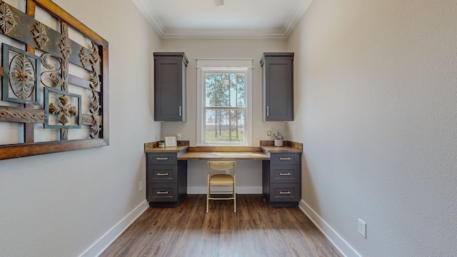 office area featuring built in desk, dark wood-type flooring, and ornamental molding