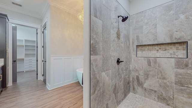 bathroom with crown molding, hardwood / wood-style floors, and a tile shower