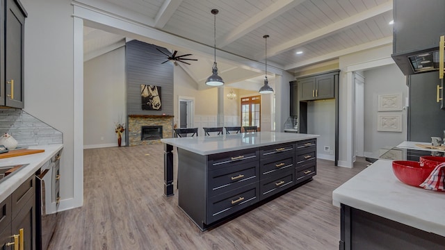 kitchen featuring a stone fireplace, gray cabinetry, decorative light fixtures, a center island, and a kitchen breakfast bar