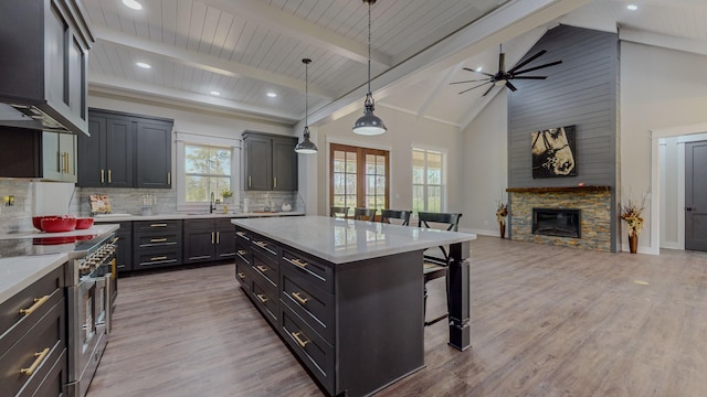 kitchen featuring a kitchen bar, high end stainless steel range, hanging light fixtures, a kitchen island, and decorative backsplash