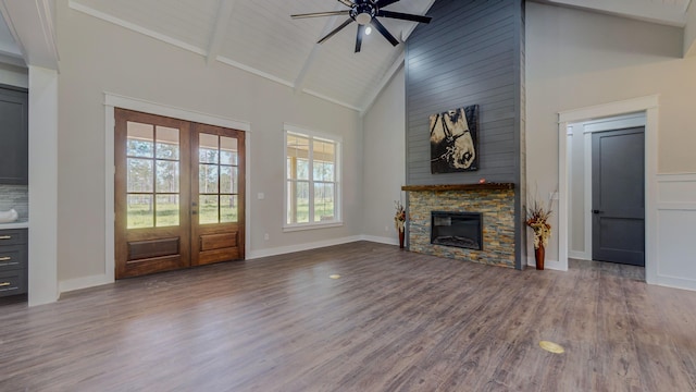 unfurnished living room with hardwood / wood-style flooring, high vaulted ceiling, a fireplace, and french doors