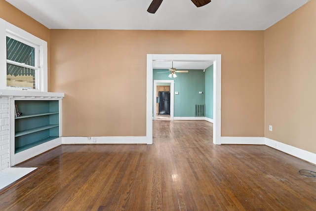 empty room with hardwood / wood-style flooring, built in features, and ceiling fan