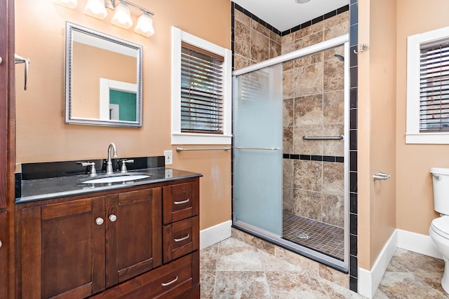 bathroom with vanity, a shower with door, and toilet