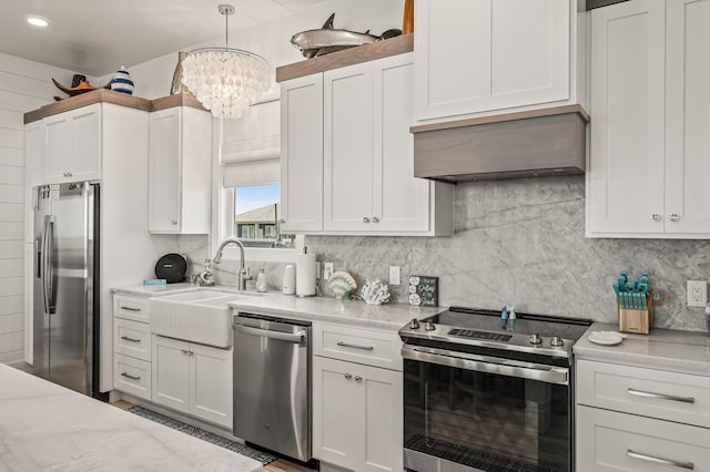 kitchen featuring light stone countertops, appliances with stainless steel finishes, sink, white cabinets, and hanging light fixtures