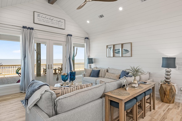 living room with french doors, ceiling fan, beam ceiling, a water view, and light hardwood / wood-style floors