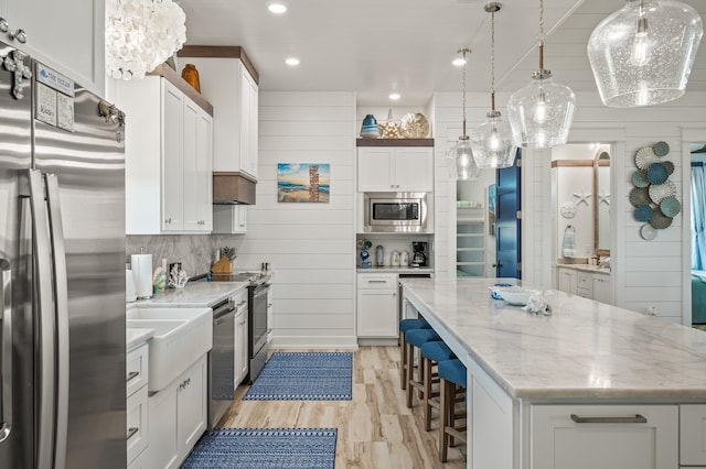 kitchen with pendant lighting, a spacious island, light hardwood / wood-style flooring, white cabinetry, and stainless steel appliances