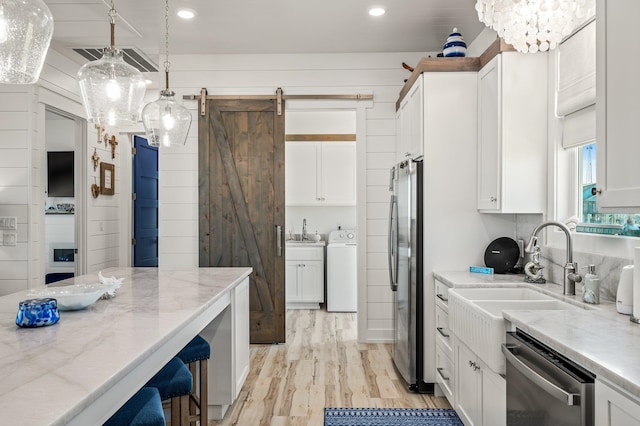 kitchen featuring a barn door, pendant lighting, white cabinets, and stainless steel appliances