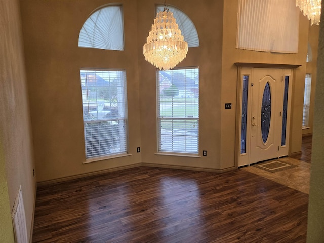 foyer with a healthy amount of sunlight, dark wood-type flooring, and an inviting chandelier