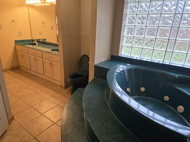 bathroom featuring toilet, vanity, a relaxing tiled tub, and tile patterned floors