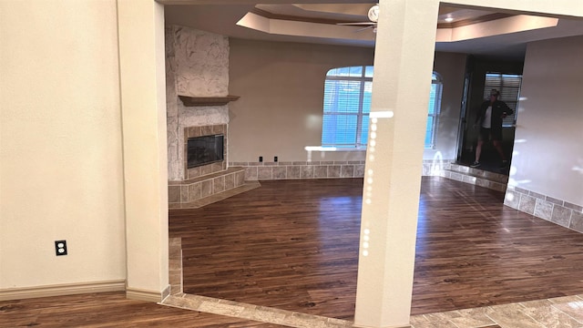 unfurnished living room with a tray ceiling, ceiling fan, and a fireplace