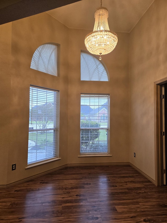 interior space with a healthy amount of sunlight, dark hardwood / wood-style flooring, a chandelier, and a high ceiling