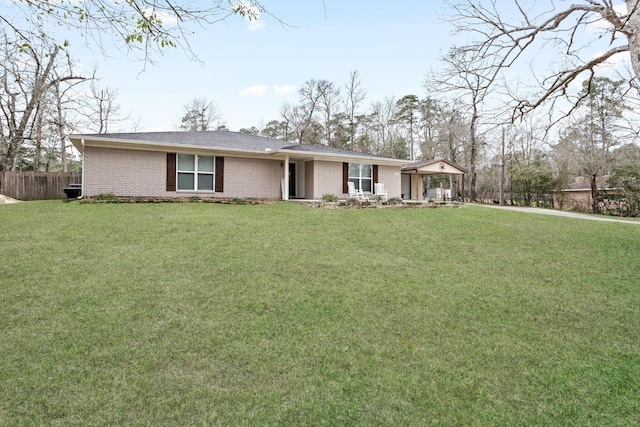 ranch-style house featuring brick siding, fence, and a front yard