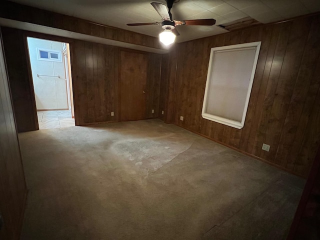 carpeted spare room featuring ceiling fan and wooden walls