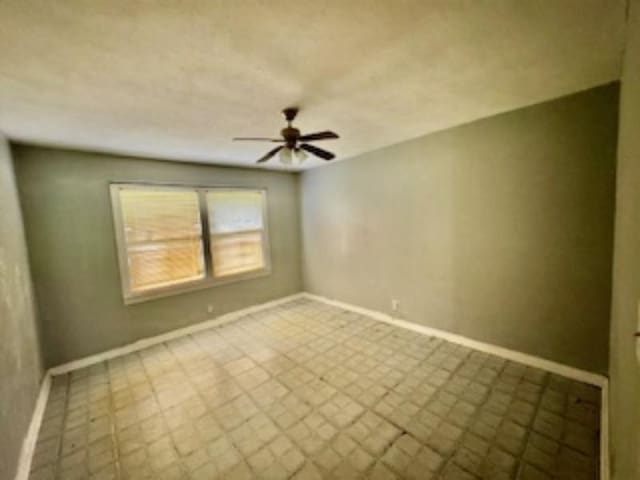 spare room with ceiling fan and baseboards