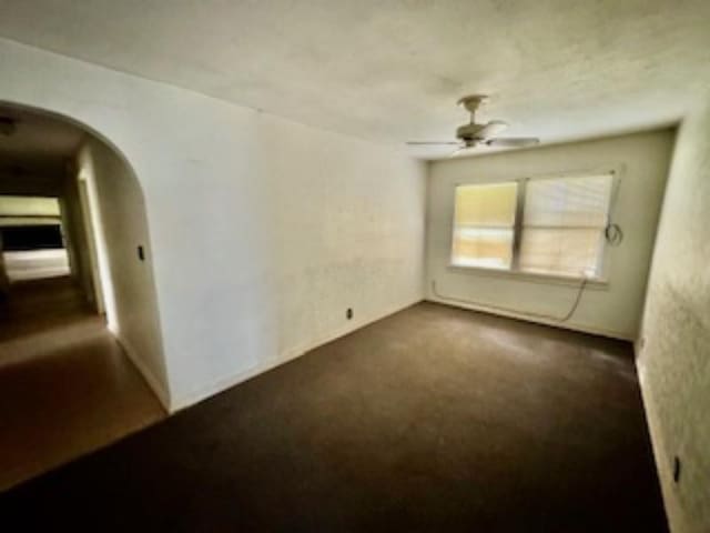 carpeted empty room with a ceiling fan and arched walkways