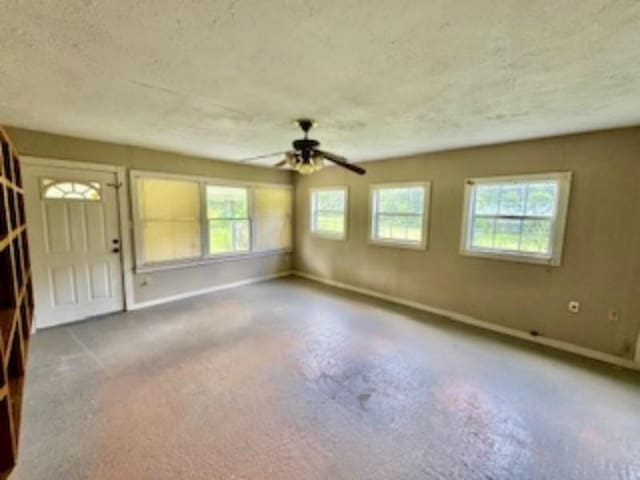 interior space featuring baseboards, a ceiling fan, and a textured ceiling