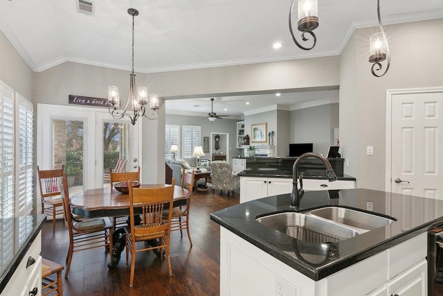 kitchen with a kitchen island with sink, crown molding, ceiling fan with notable chandelier, white cabinets, and sink