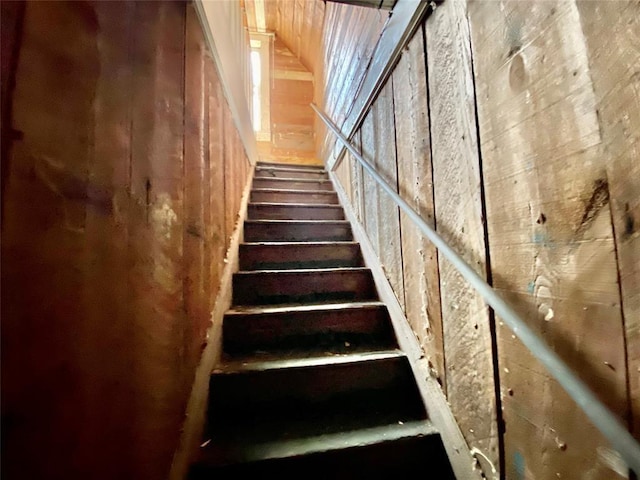 staircase featuring wood walls