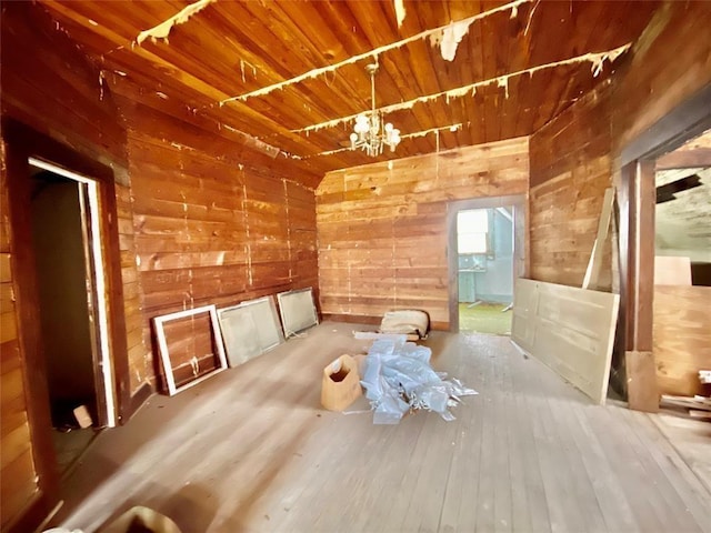 interior space with wood-type flooring, a notable chandelier, wooden ceiling, and wood walls