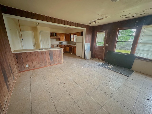3 Inwood Cir Unit B, Orange, TX 77630 - kitchen with freestanding refrigerator, a peninsula, plenty of natural light, brown cabinets, and wood walls