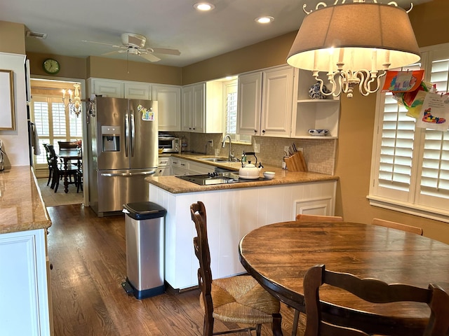 kitchen with kitchen peninsula, sink, white cabinets, and stainless steel refrigerator with ice dispenser