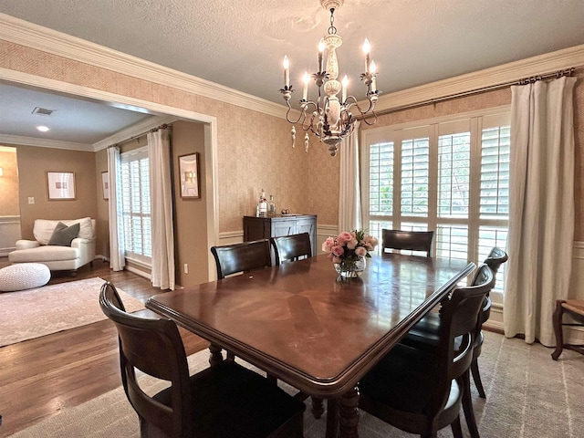 dining room with plenty of natural light, wood-type flooring, ornamental molding, and an inviting chandelier