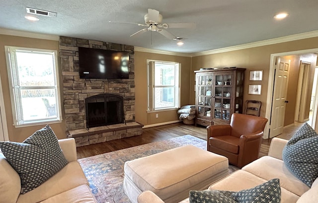 living room with a wealth of natural light, ceiling fan, crown molding, a fireplace, and hardwood / wood-style flooring