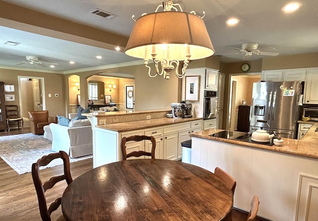 dining room featuring wood-type flooring, ceiling fan with notable chandelier, and ornamental molding