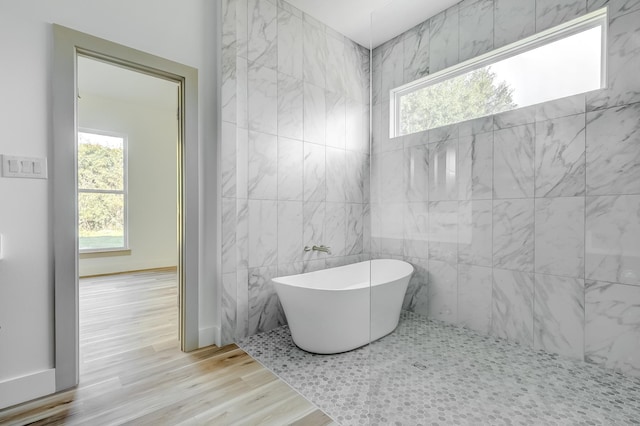 bathroom with wood-type flooring, tile walls, and a bathing tub