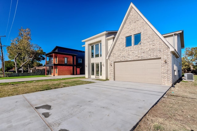 view of front of property featuring a front lawn, a garage, and central AC