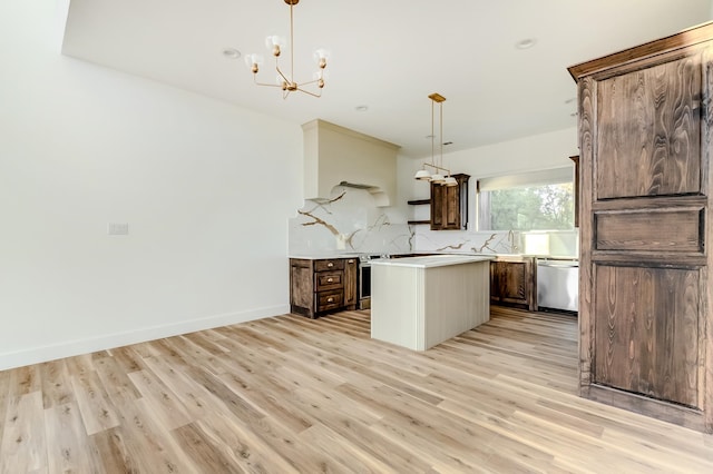 kitchen with hanging light fixtures, a kitchen island, stainless steel appliances, and light wood-type flooring