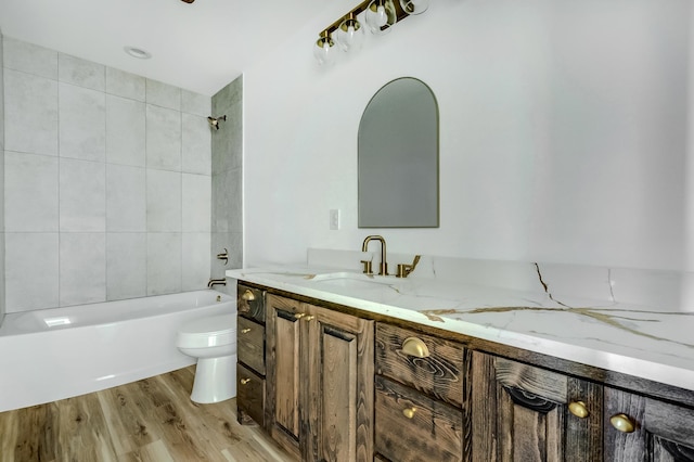 full bathroom with vanity, hardwood / wood-style floors, tiled shower / bath combo, and toilet