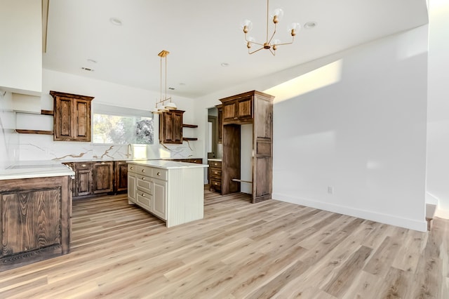 kitchen with sink, decorative light fixtures, light hardwood / wood-style flooring, a notable chandelier, and a kitchen island