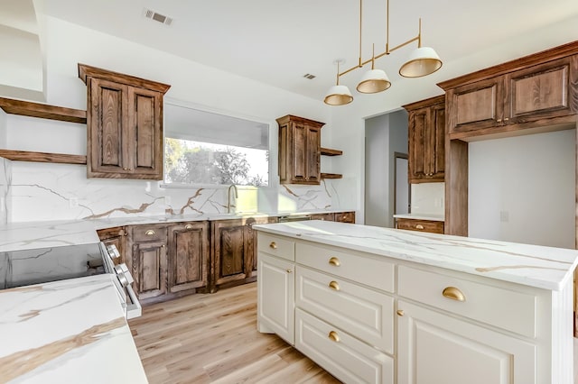 kitchen featuring decorative backsplash, light stone counters, light hardwood / wood-style floors, white cabinetry, and hanging light fixtures